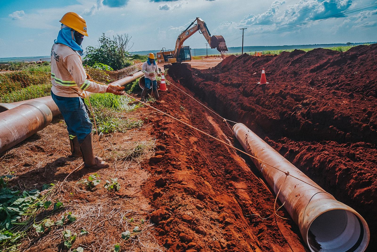Equipe instalando tubulação de adutora enterrada
